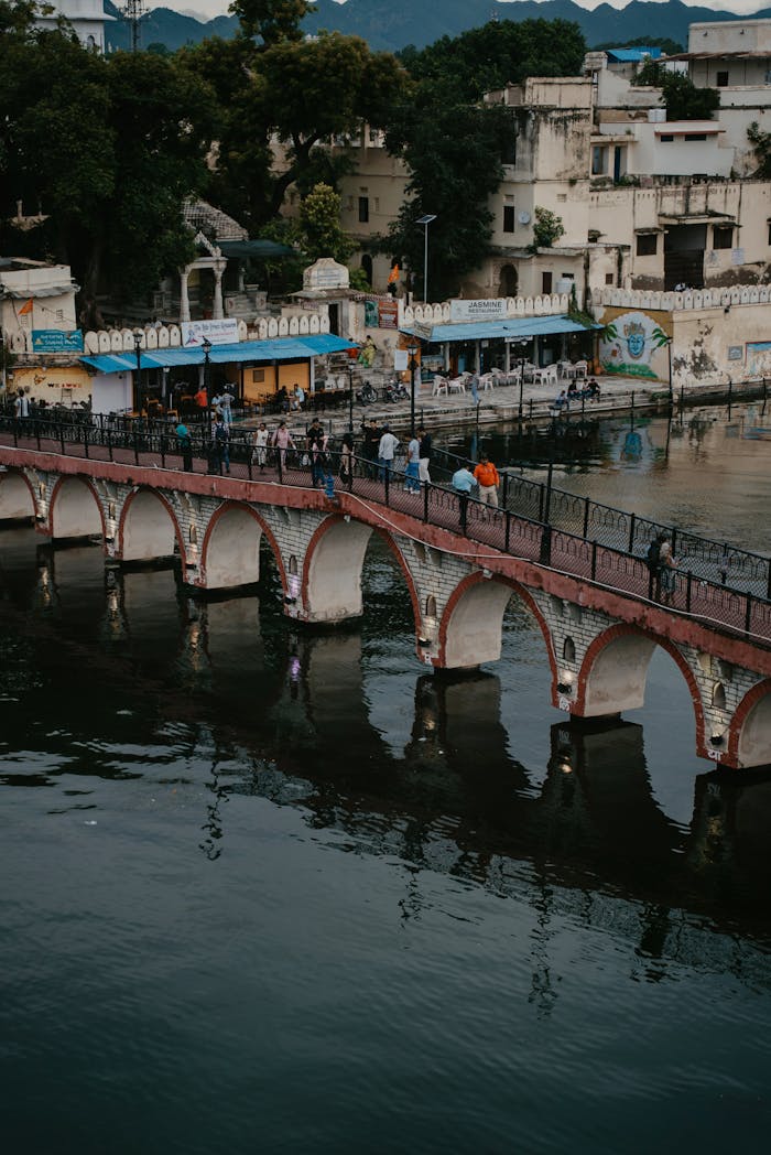 Aerial view of a historic bridge and buildings over a serene lake in Udaipur, Rajasthan.