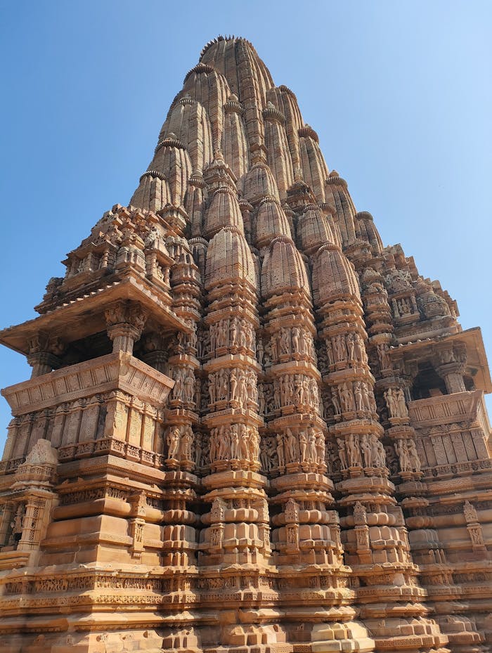 Stunning view of the intricate sandstone architecture of a Khajuraho temple in India under a clear blue sky.